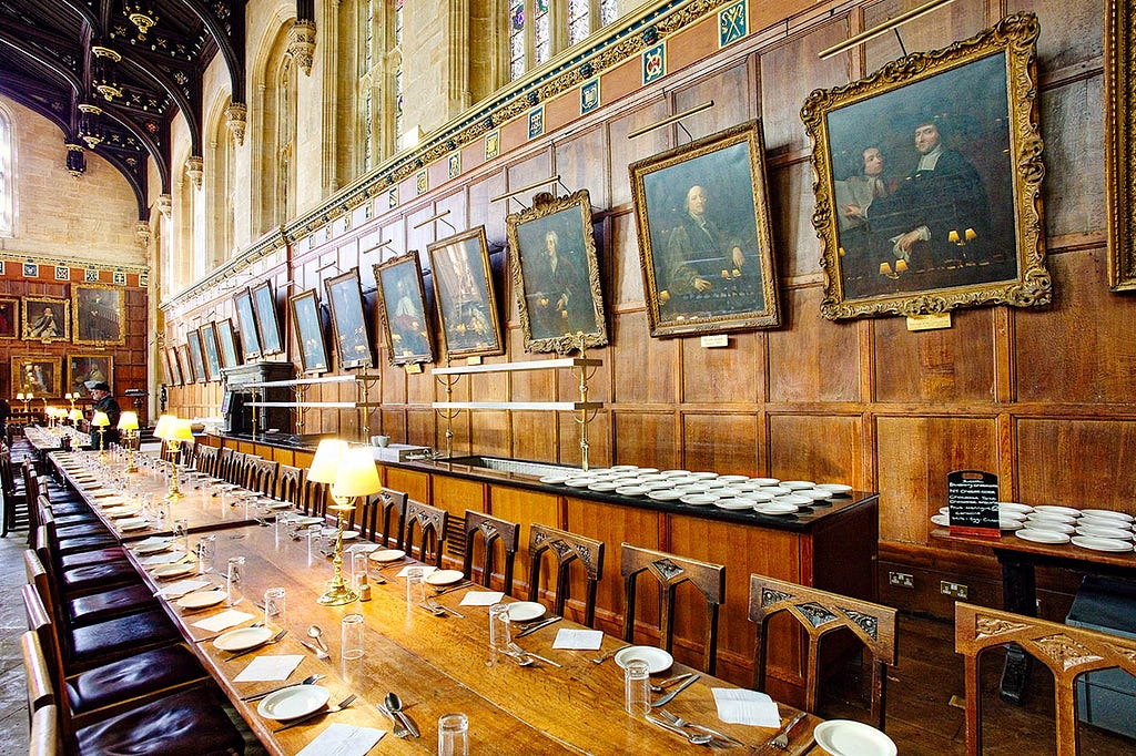 a dining table set for 40 people with a line of painted portraits along the wall