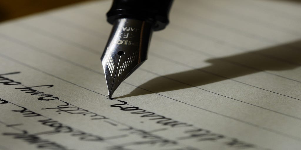 Close-up of an ink nib writing on lined paper.