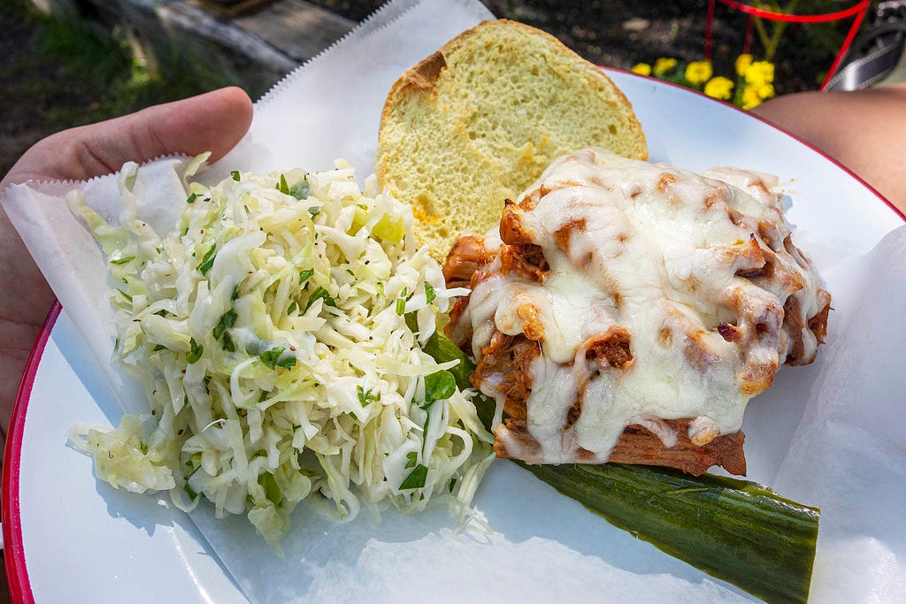 an open pulled bbq sandwhich with a side of coleslaw