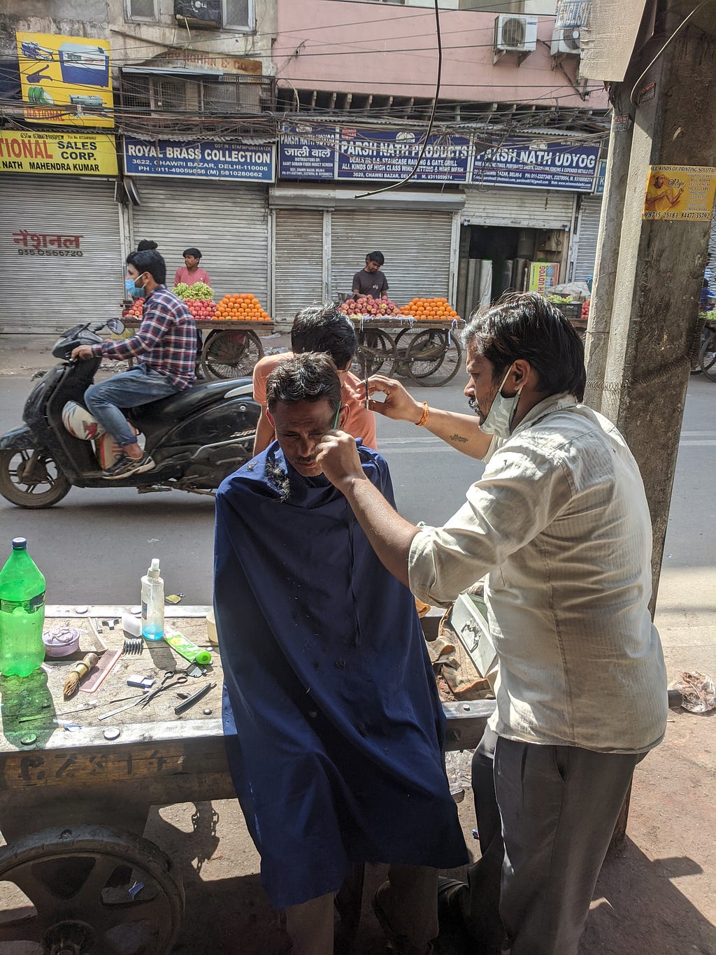 Barber cutting hair in middle of the road in Old Delhi