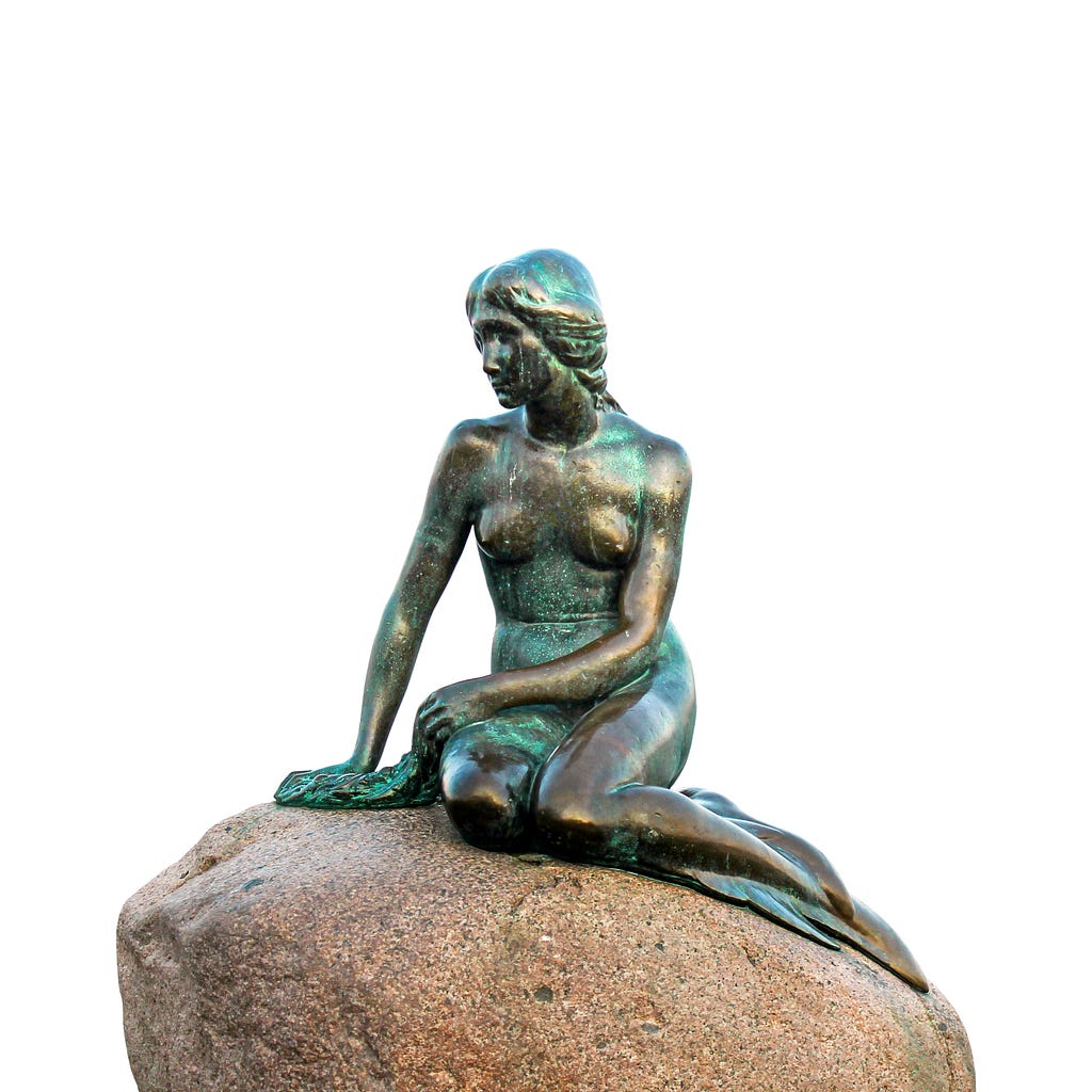 Image of the Little Mermaid statue (representing the Loreley), a bronze sculpture depicting a mermaid sitting on a rock. The statue shows a mermaid with a serene expression, her upper body resembling a human and her lower body featuring a fish tail.