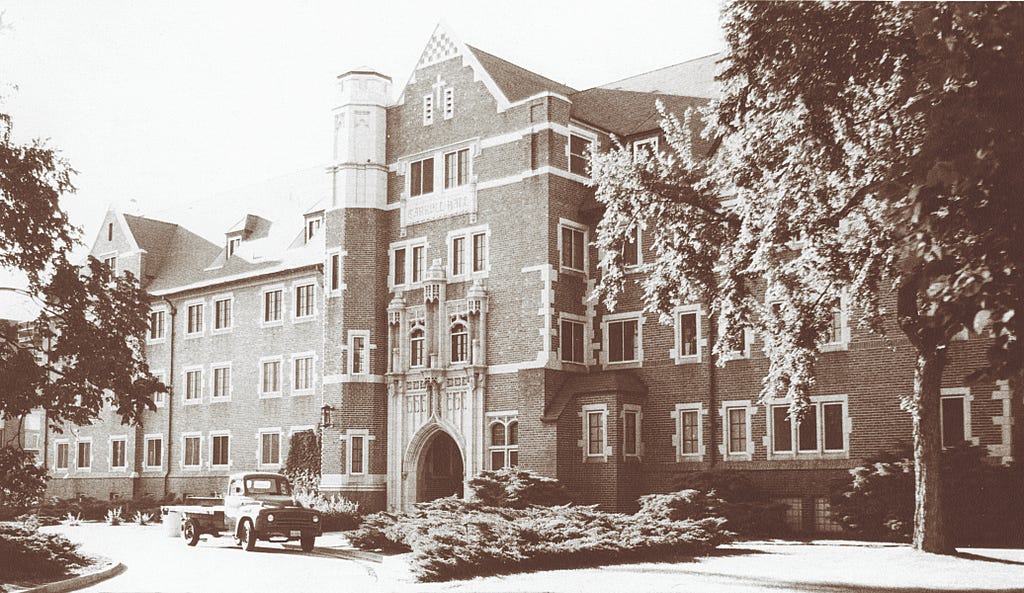 black and white photo of the exterior of Carroll Hall with old fashioned truck parked out front