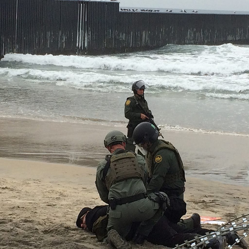 Jorge Bautista is face down on the sand being arrested by CBP agents