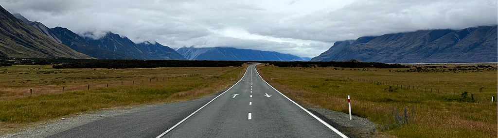 An open road stretching into the distance under a grey sky.