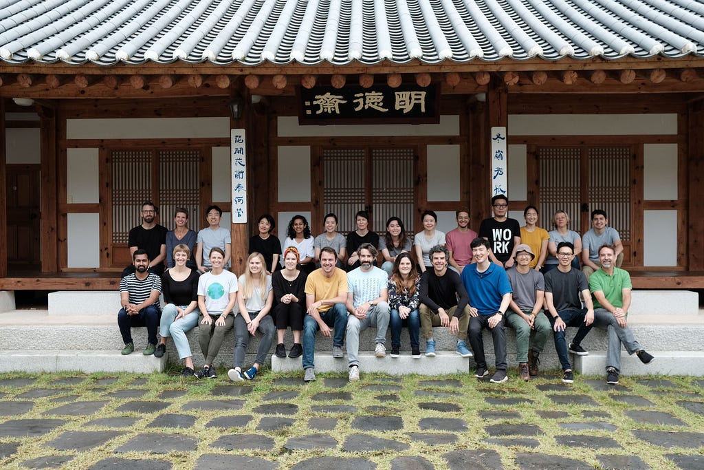 A team of people sitting under a traditional Korean roof awning