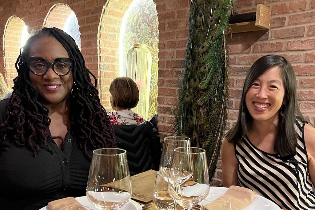 Photo of Monica and Priscilla, co-directors, sitting at a table at a restaurant.