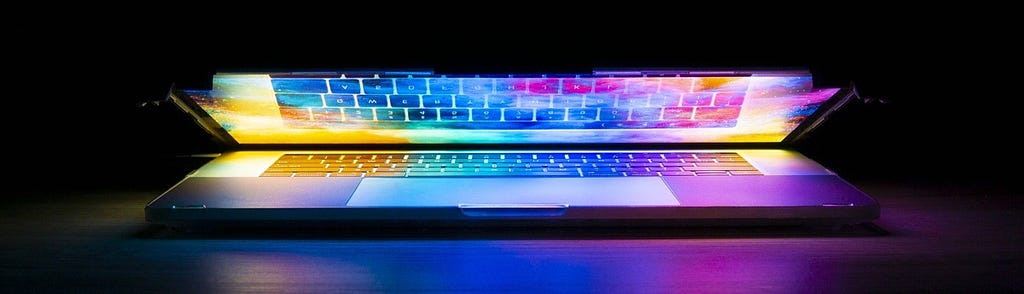 Image: A half-closed laptop glowing with colors.