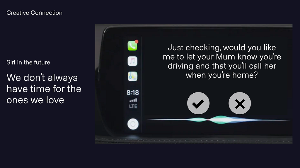 A screenshot of Apple Carplay inside a car. The screen is black with white text on it. It shows text, two large white buttons with a tick and a cross as well as some wavy lines indicating Siri chat. The words say “Just checking, would you like me to let your Mum know you’re driving and that you’ll call her when you’re home?”