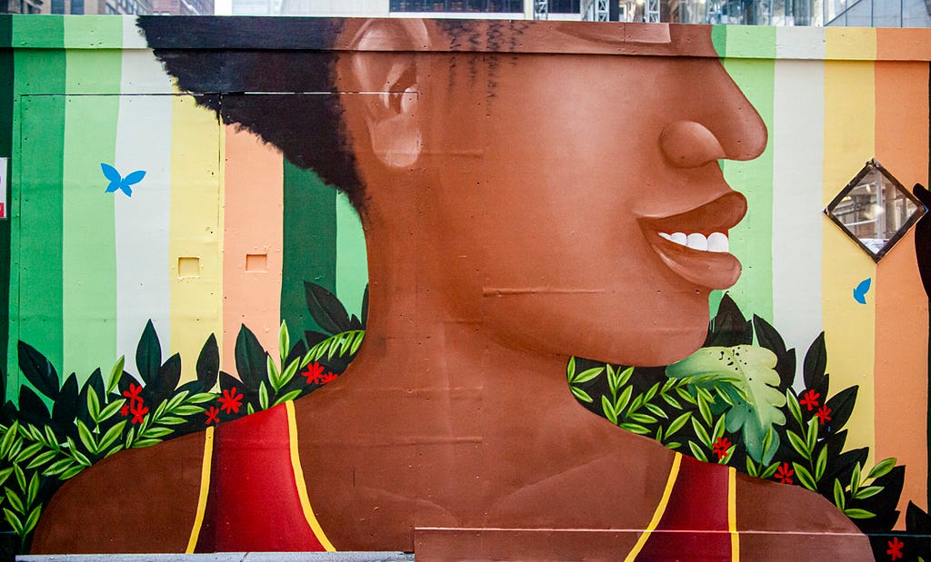 A painted representation of Agatha Felix smiling surrounded by tropical leaves and two brids.