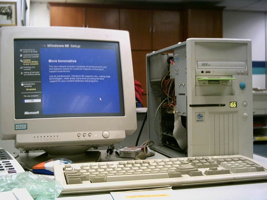 A late 90s ‘tower’ PC. It is beige coloured. The screen is a 16" CRT display. The keyboard is a standard IBM-style keyboard, without special Windows function keys. The tower PC includes a 3.25" “floppy” disk drive, a 50x CD-ROM and an Intel Pentium Processor.