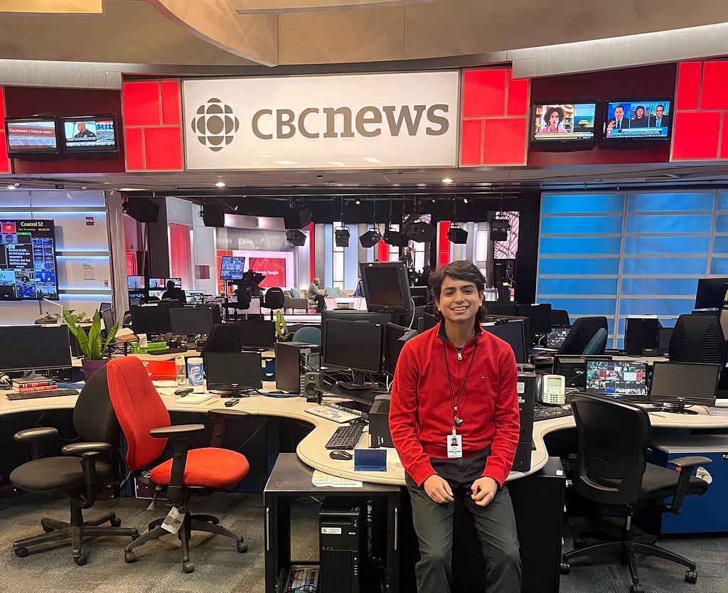 Luis sitting on a desk in the CBC newsroom