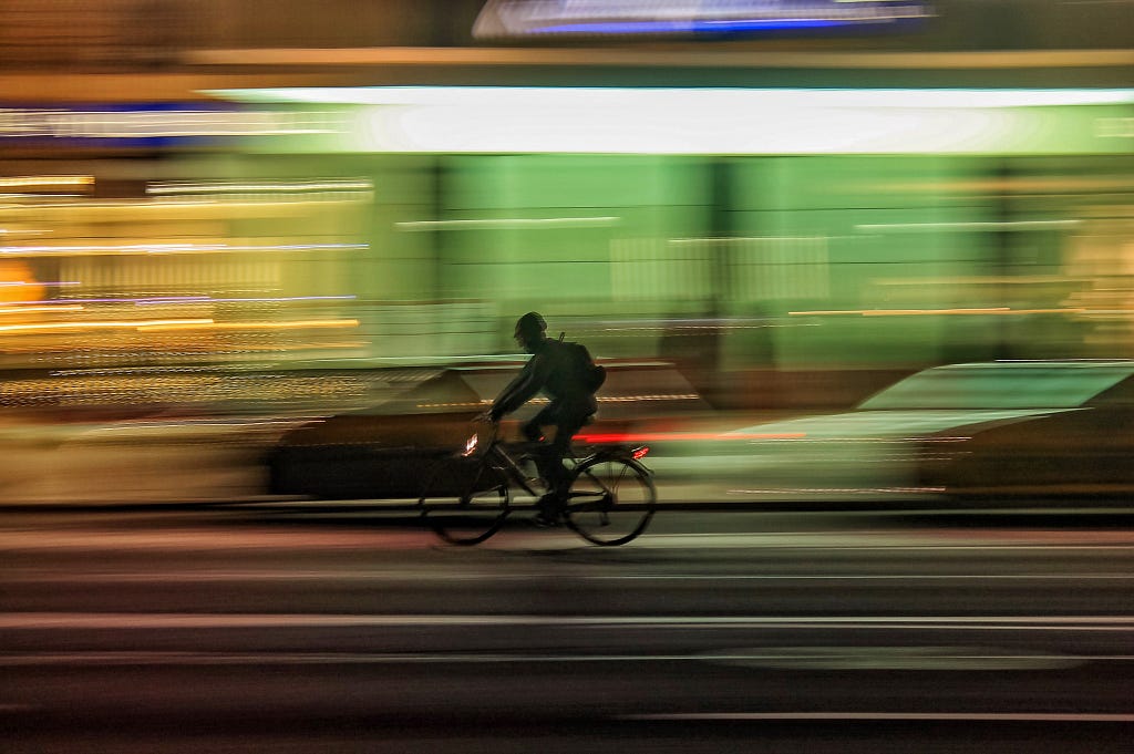 A biker rides on a street with blurred lights