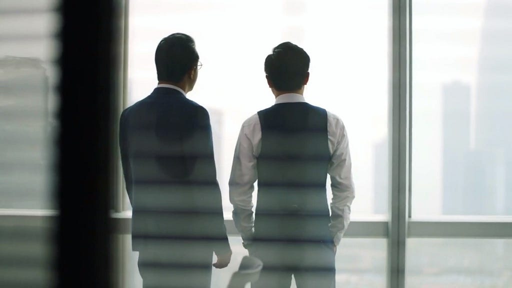 two men talking as facing windows