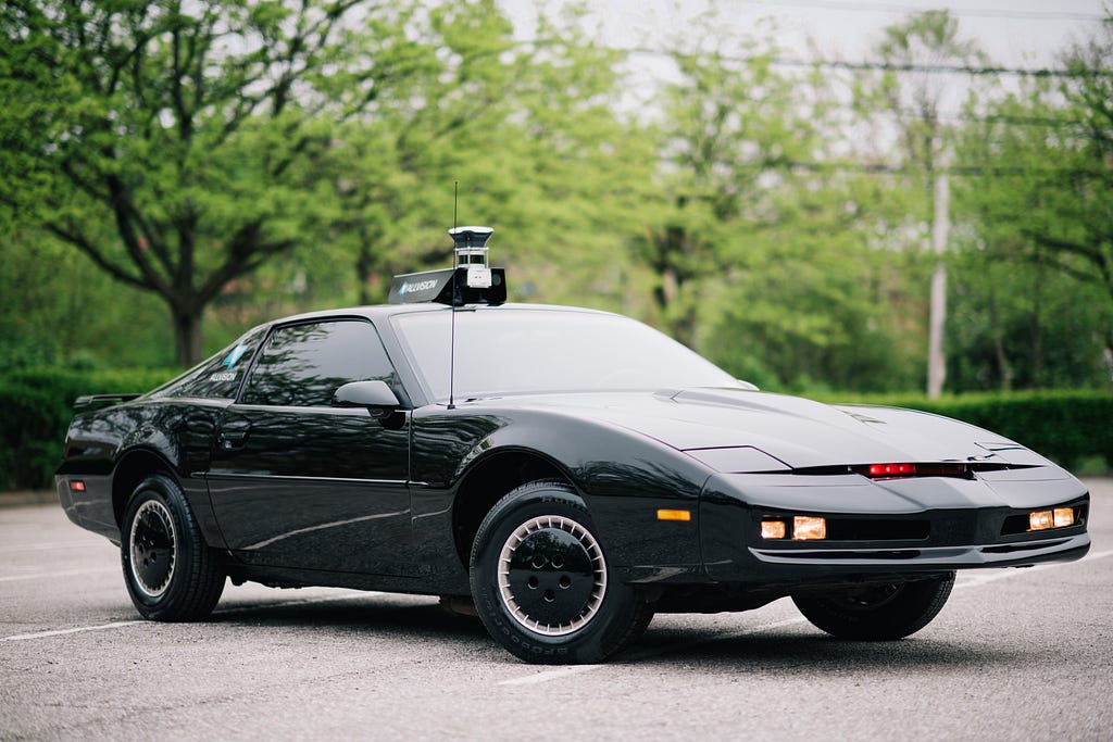 A Pontiac Firebird Trans Am with autonomous vehicle LIDAR technology affixed to the roof.