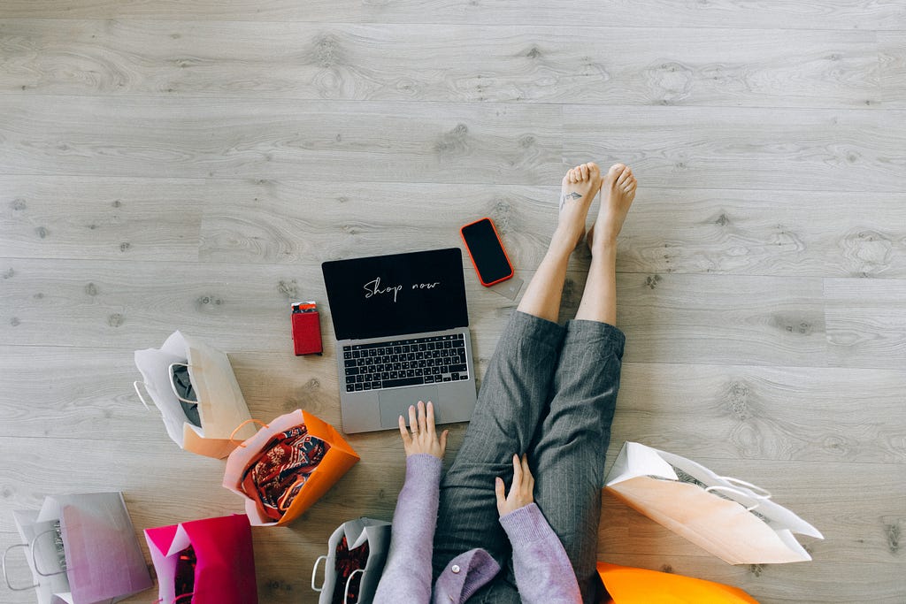 a person surrounded by shopping bags and with a laptop for online shopping