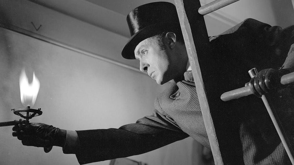 a black and white photo of a man adjusting a gaslight