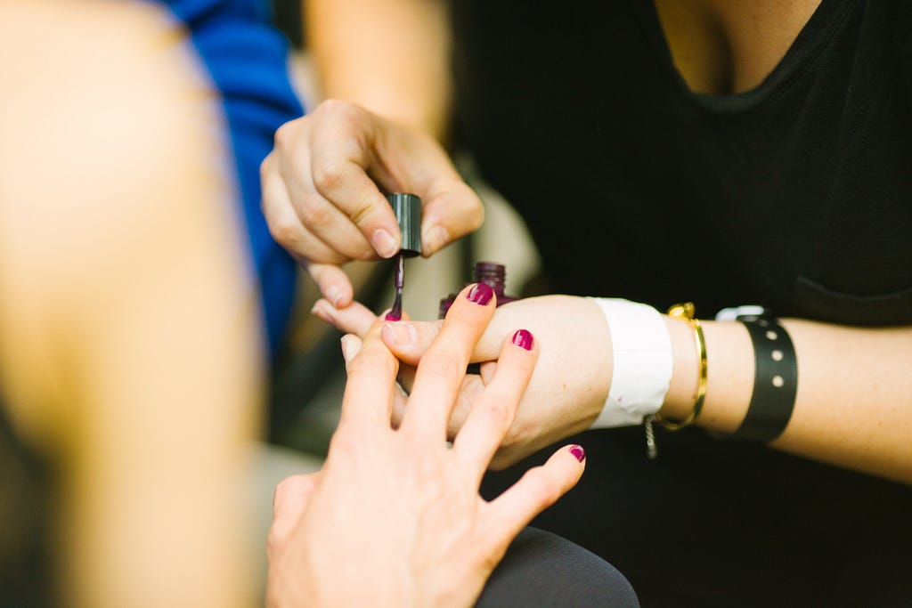 Woman painting other woman’s nails to reduce mental stress