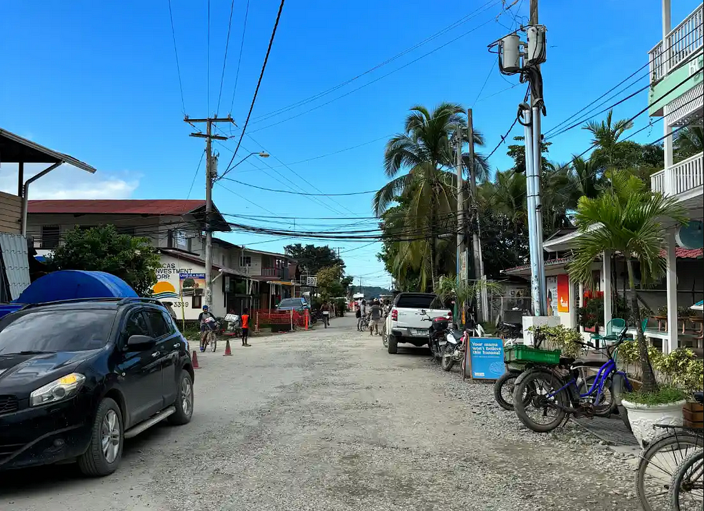 The main street in Bocas Town, Isla Colon, Panama, with a blue sky, two cars and some bicycles