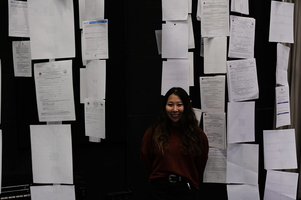 A women stands in front of rows of forms.