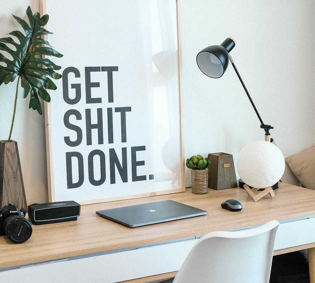 Working desk with laptop with a “Get shit done” poster