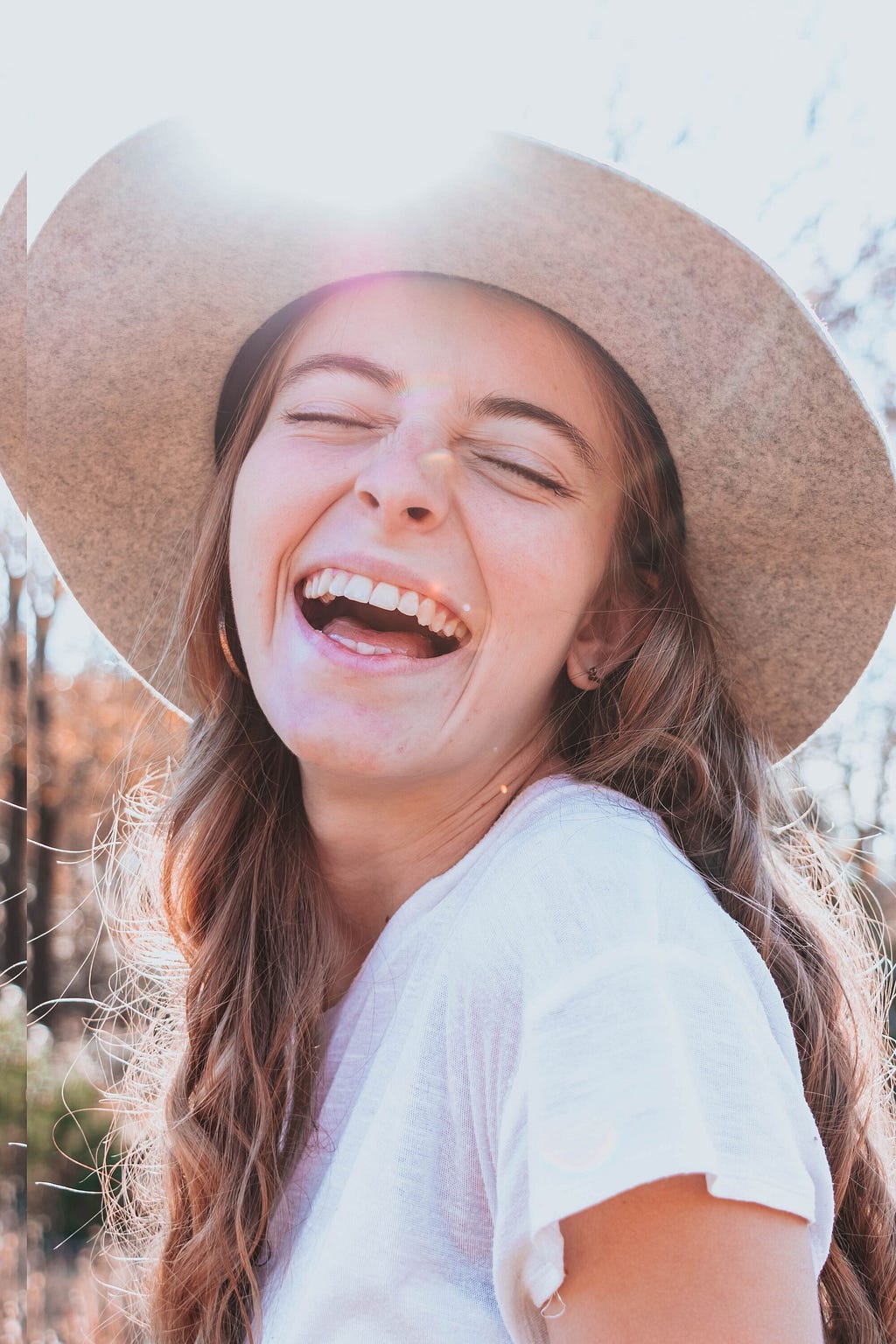 A smiling young lady with straw hat showing off her new smile from Orlando Smile Factory