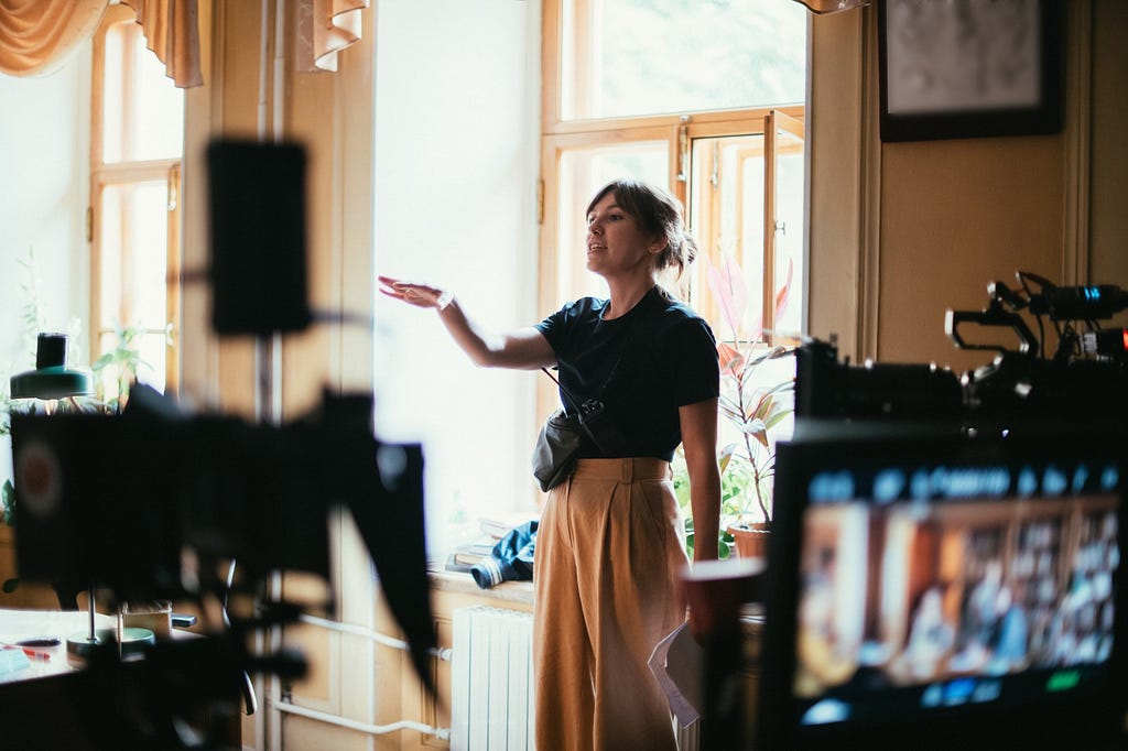 A woman directs actors on a film set.