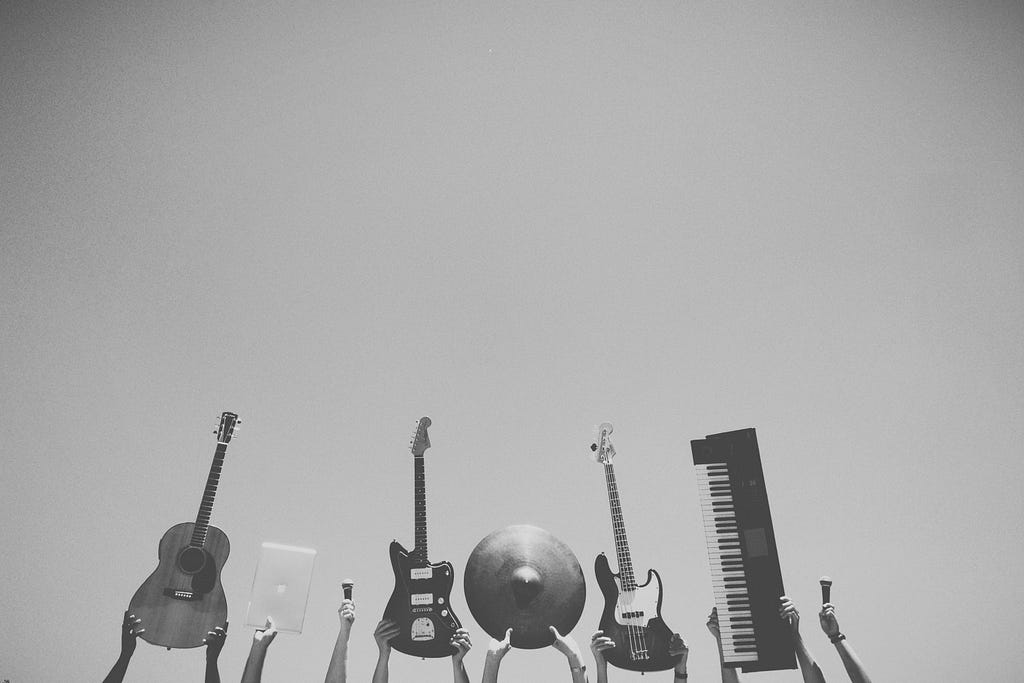 Black and white photo of peoples hands holding up musical instruments.