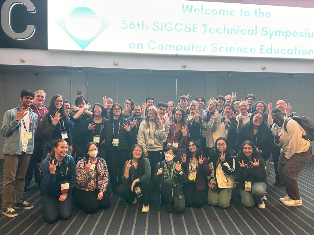 Roughly 40 UW attendees, all engaged in research and teaching, across multiple units at UW, posed for a group photo, making UW signs with their fingers.
