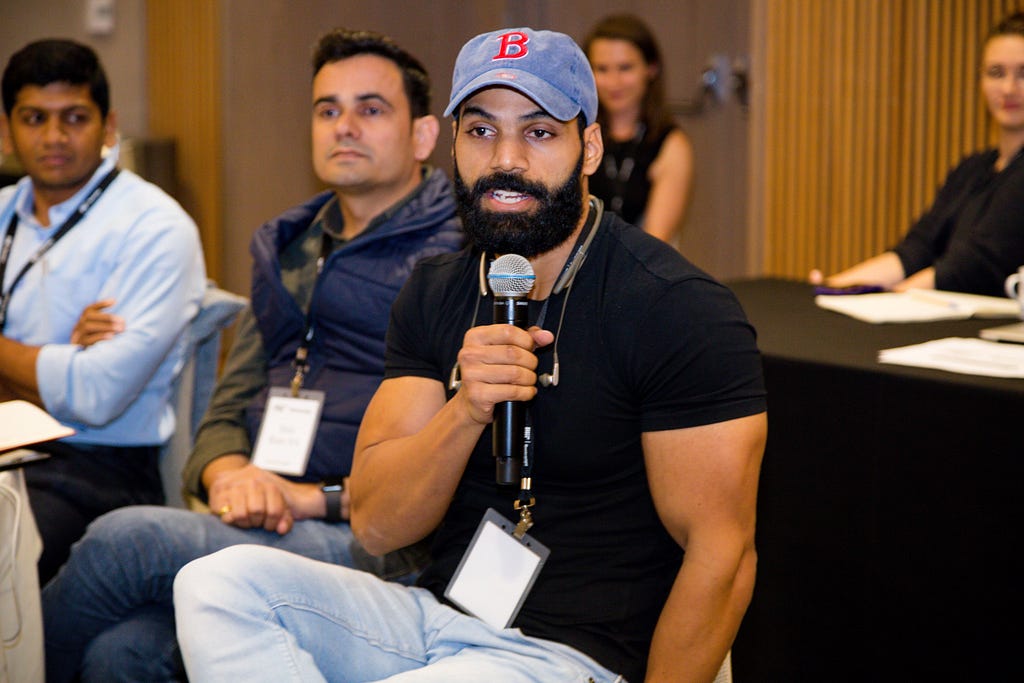 Candid photo of Jitendra Chouksey speaking into a microphone while seated in an audience.