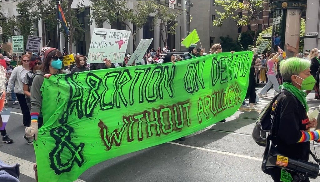 The participants raised the signs “abortion on demand & without apology” at 2022 San Francisco pride parade.2022年舊金山LGBT驕傲大遊行隊伍中，遊行群眾拉著支持墮胎權的大布條：「我們需要墮胎權，而且不需要道歉！」