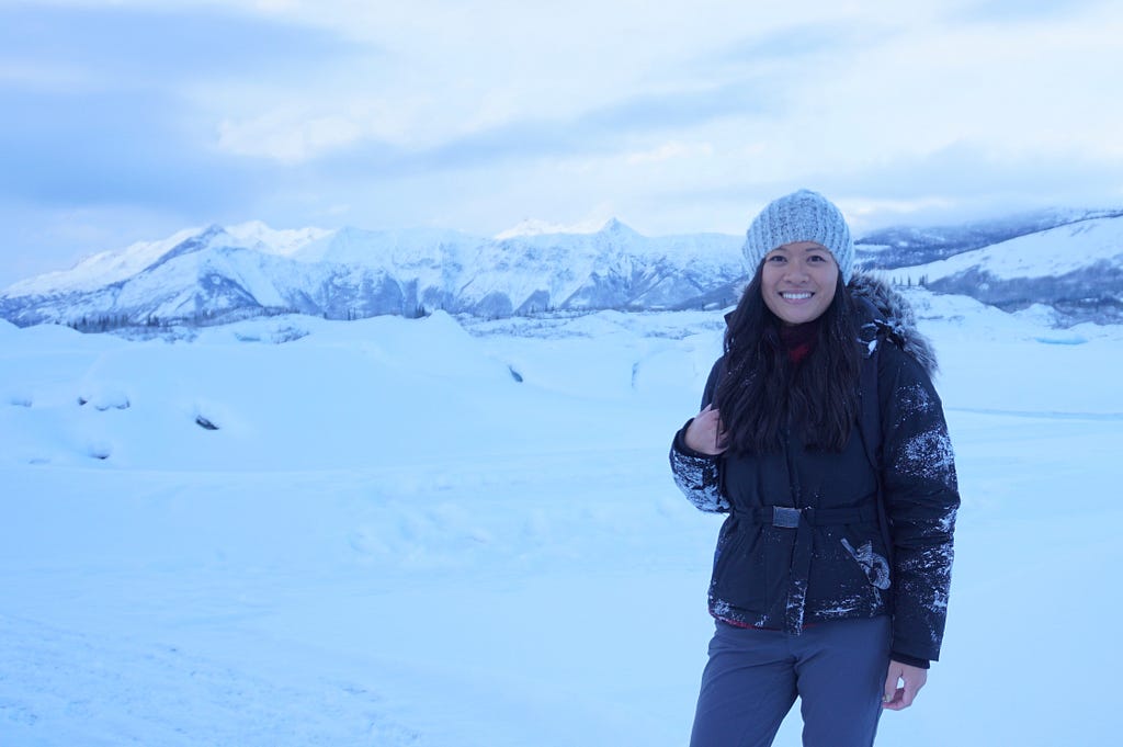 An American female traveler posing for a picture on the tundra in the snowbanks on a trip