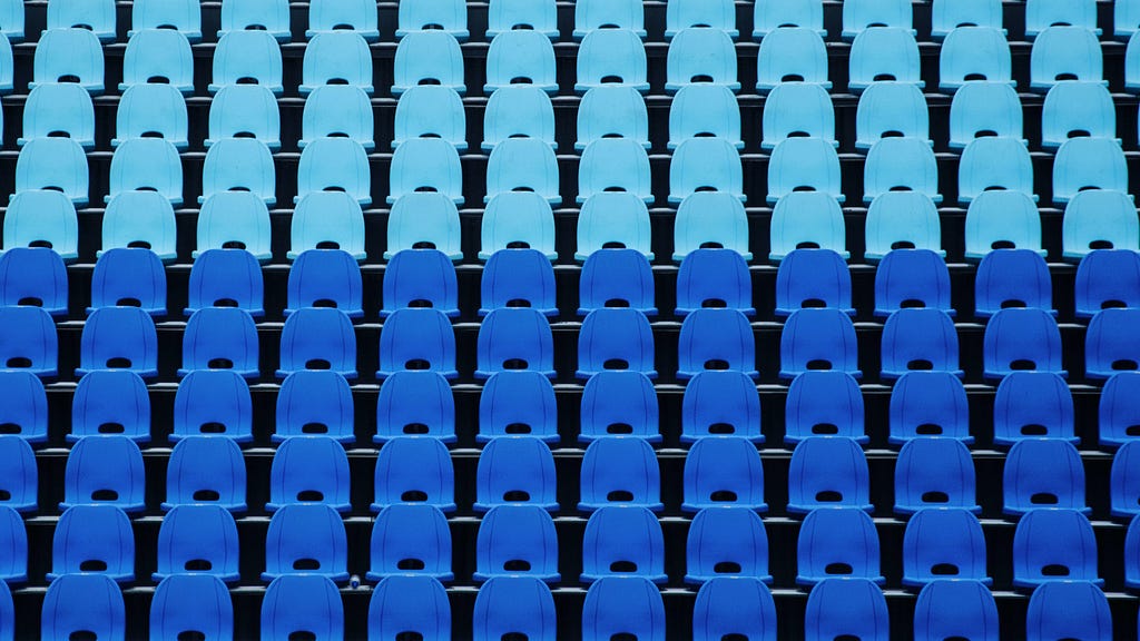 Image of multiple rows of empty blue stadium seats