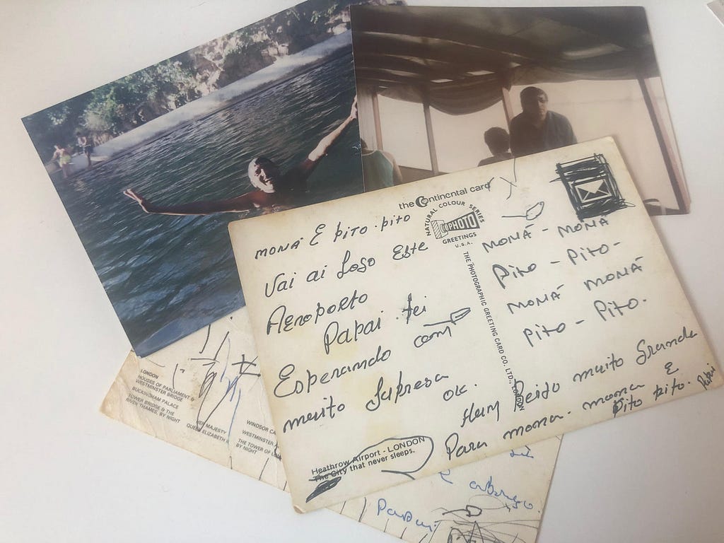 A photograph of a man in a swimming pool with his arms raised in joy, next to another photograph of the man with sunglasses sat. Two postcards on top of one another with writing in portuguese and children’s scribbles