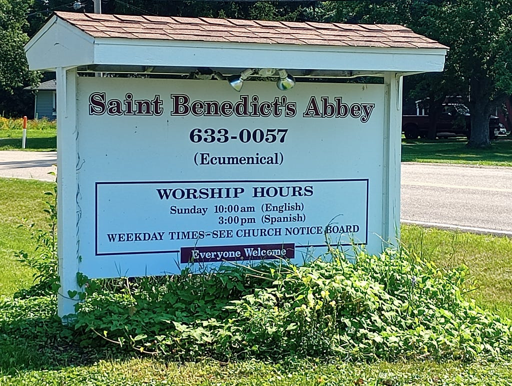 Sign outside of St. Benedict’s Abbey in Bartonsville, IL offers the hours of worship and says, “Everyone Welcome.”