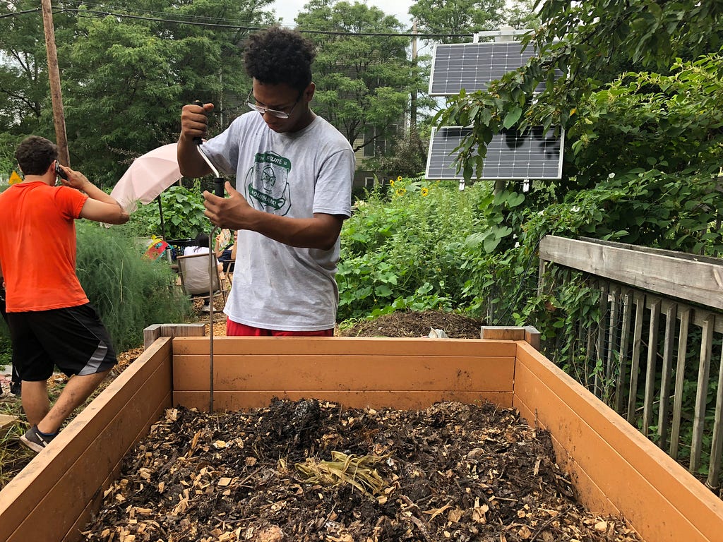 A young black man assembles a community garden bed.
