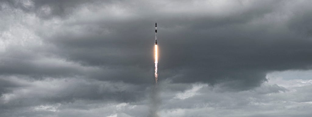 SpaceX rocket launching into storm clouds.