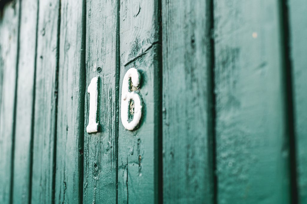 Number 16 on a green wooden door.