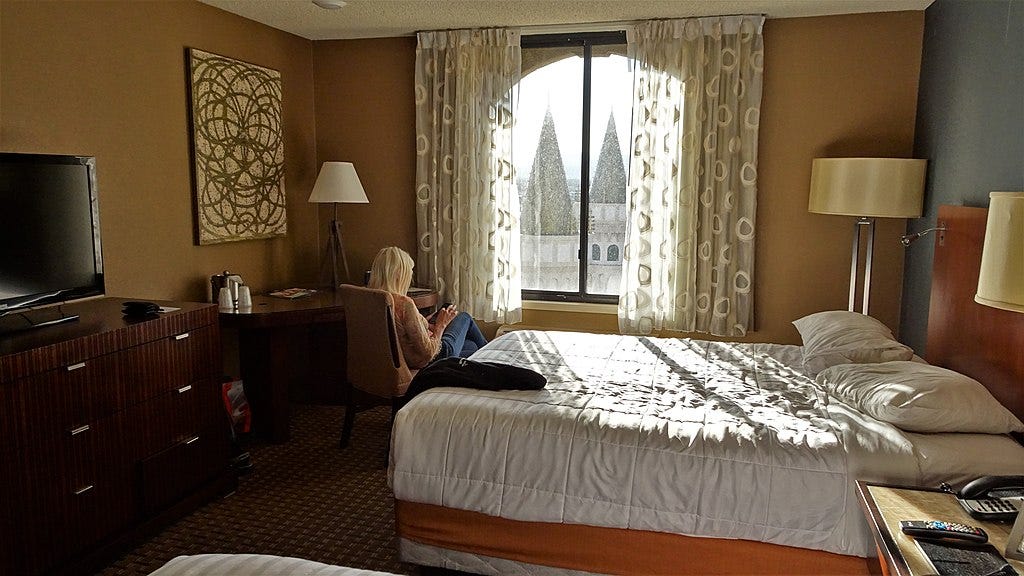 A woman checks her phone in the Excalibur’s Royal Towers hotel room overlooking the turrets of the Excalibur castle