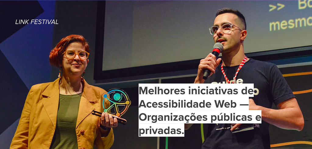 Foto da Ana Cuentro com troféu e Paulo Aguilera falando no microfone. Eles estão recebendo o prêmio: melhores iniciativas de Acessibilidade Web- Organizações públicas e privadas.