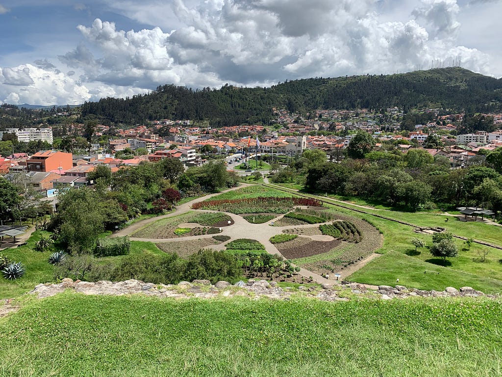 Wander and enjoy the lush garden of the Museo de Pumapungo of Cuenca. The city of Cuenca can be seen beyond the garden.