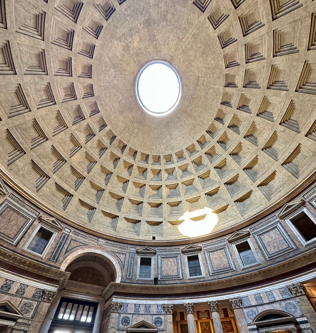 The roof of the Pantheon in Rome with sunlight casting a bright spot on the side wall.