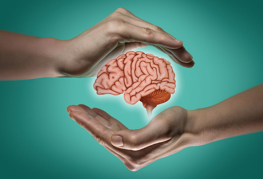 Two hands cupped protectively around, but not touching, a graphic cartoon image of a human brain