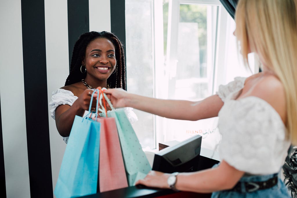 sales assistant handing customer her bags.