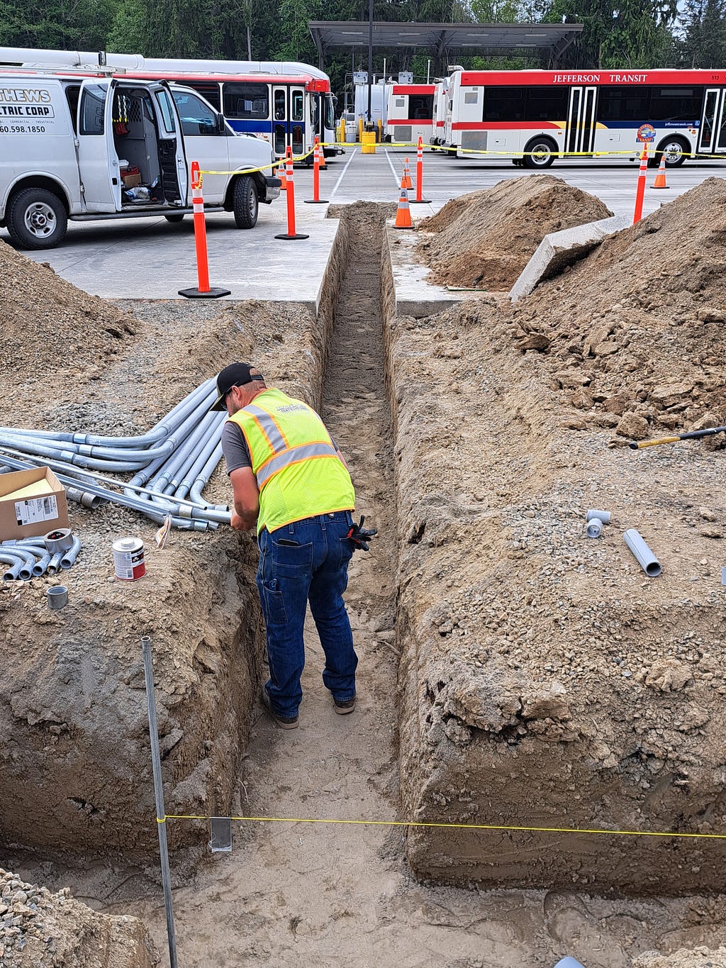 A worker digs a trench for EV charging infrastructure at a Jefferson Transit Authority station in Jefferson County.