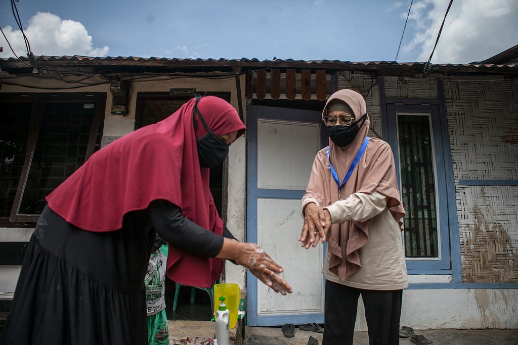 Sri Rostiaty was mentoring Farida on a handwashing exercise in front of her house while Farida’s son was observing the exercise up close. Photo by Andri Ginting