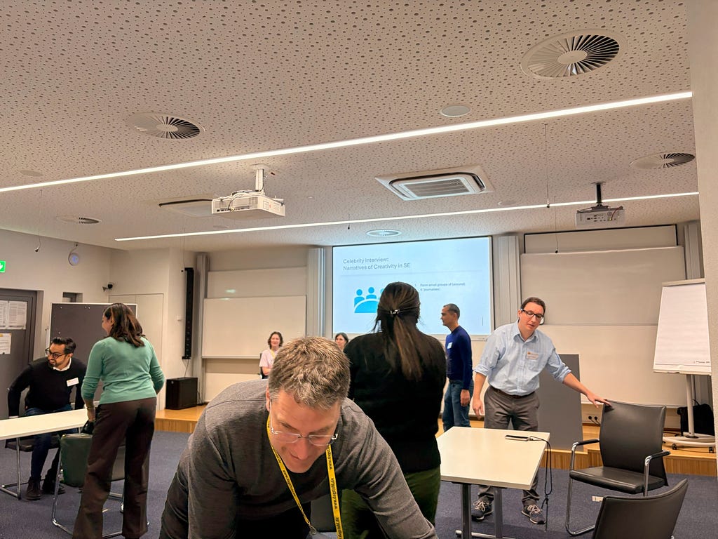 Several scholars moving tables and negotiating the placement of chairs.