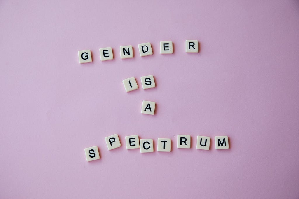 gender is a spectru, — Photo by Laker : https://www.pexels.com/photo/inscription-gender-is-a-spectrum-made-of-scrabble-letters-against-pink-background-6156944/