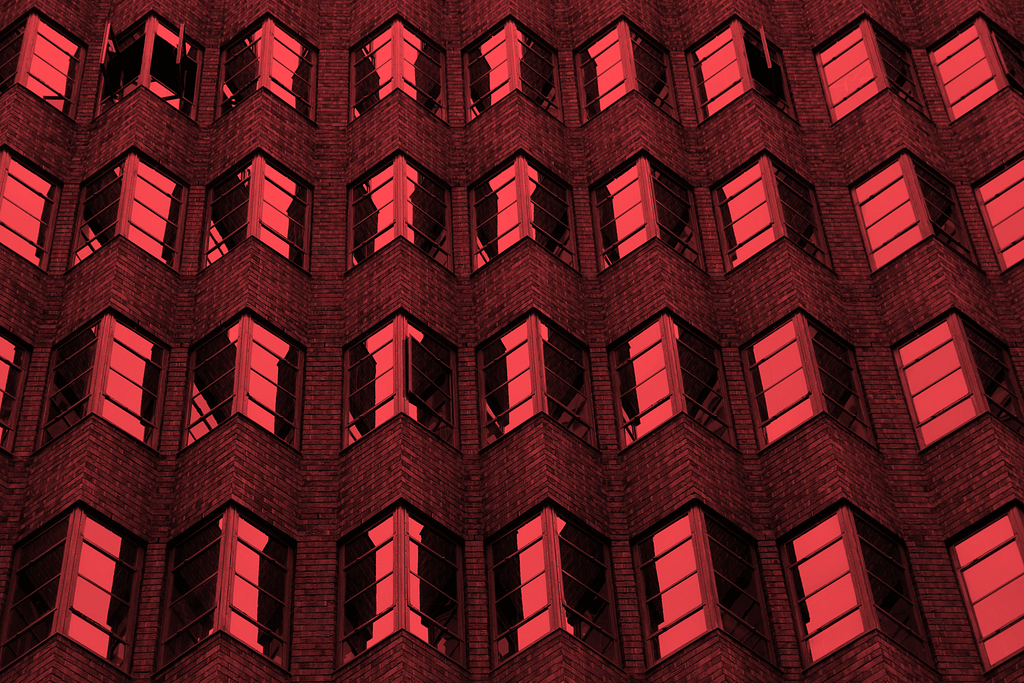 Close up of a building with a series of squared windows overlaid with a red filter.
