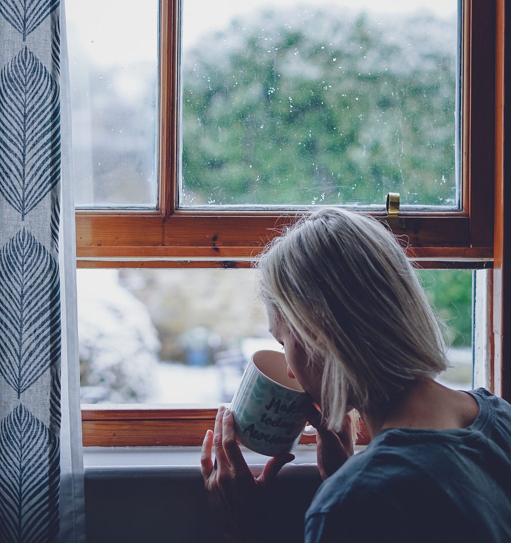 A lady enjoying her cup of coffee near window