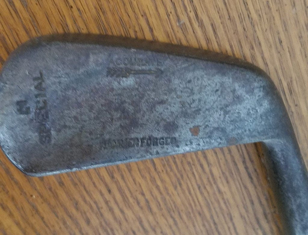 A picture of a forged iron golf club head with an inscription. Photo by author.